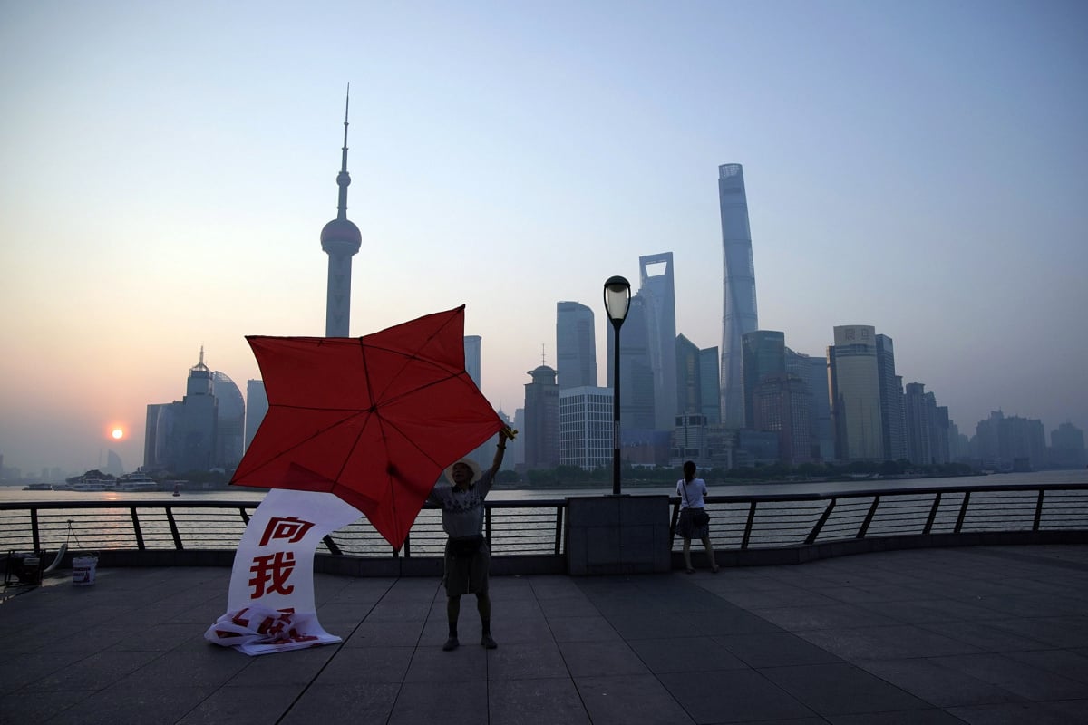 A man poses with a kite shaped like the red star of China's People's Liberation Army on the bund in front of the financial district of Pudong in Shanghai