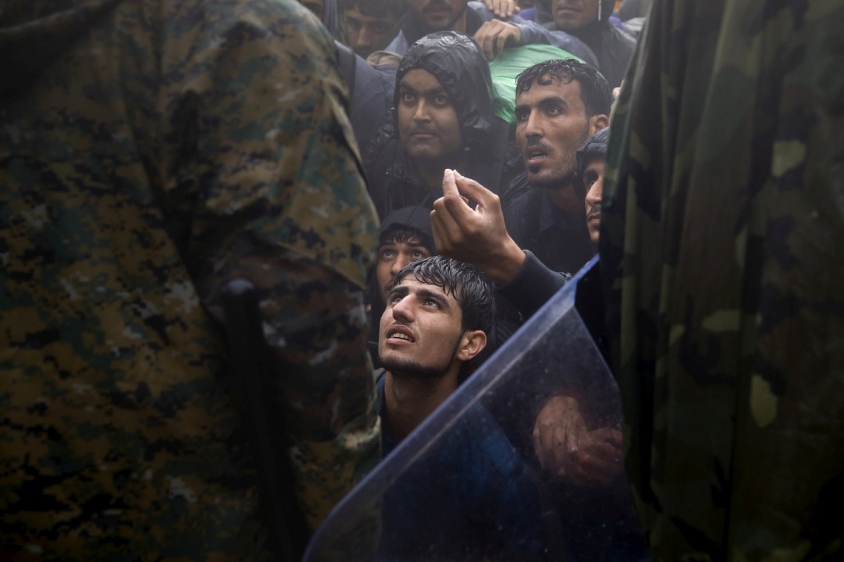 Migrants and refugees beg Macedonian policemen to allow passage to cross the border from Greece into Macedonia during a rainstorm, near the Greek village of Idomeni, September 10, 2015. REUTERS/Yannis Behrakis/File Photo