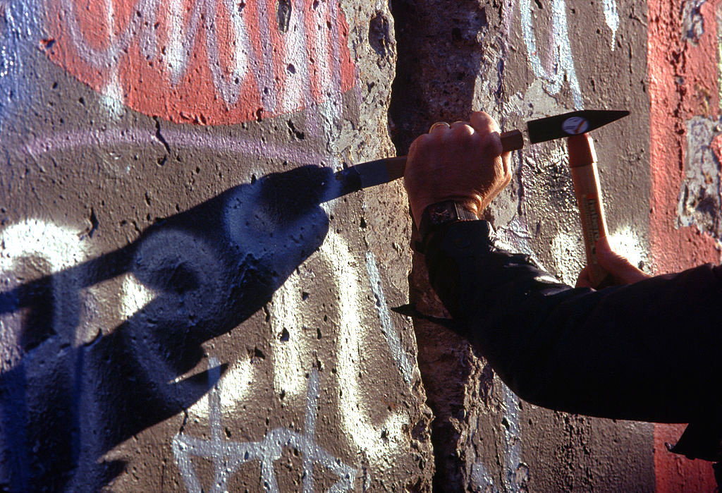 A man from West Berlin uses a hammer and chisel to chip off a piece of the Berlin Wall in 1989. Wikimedia Commons/Public domain