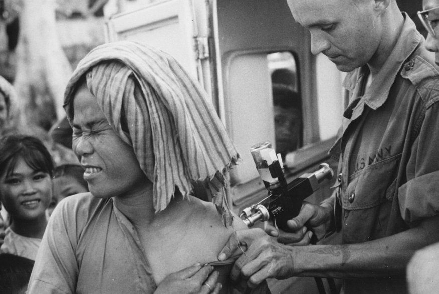 A U.S. Navy hospital corpsman, member of a USAID military health team, inoculates a flood refugee against cholera at the refugee center on Nui Sam mountain, Chau Doc province., 1966. U.S. Information Agency via National Archives and Records Administration