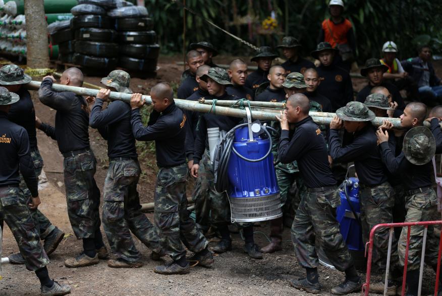 Military personnel carry a water pump machine as they enter the Tham Luang cave complex, where 12 boys and their soccer coach are trapped, in the northern province of Chiang Rai, Thailand, July 6, 2018. REUTERS/Athit Perawongmetha
