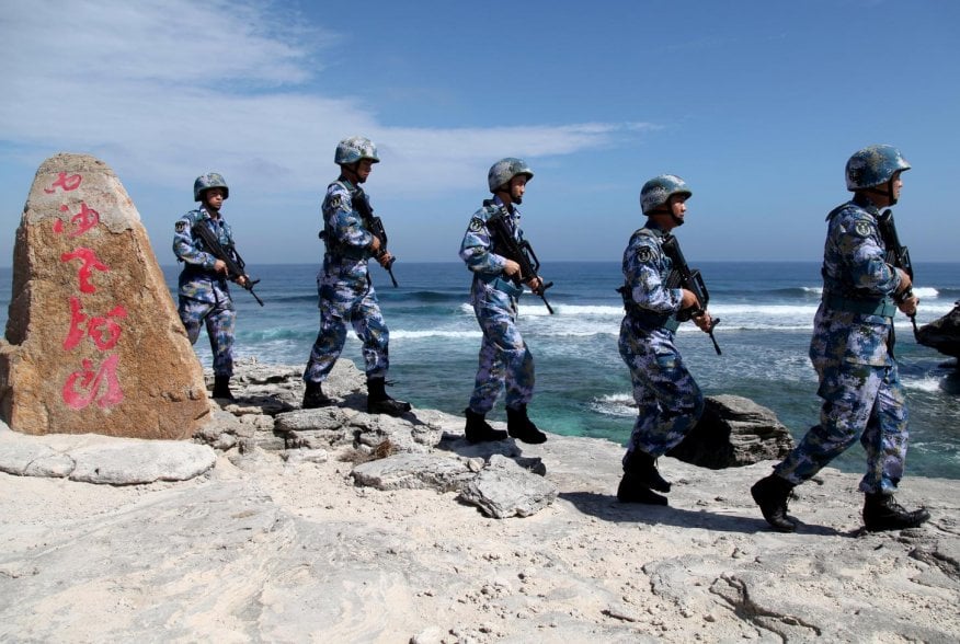 Soldiers of China's People's Liberation Army (PLA) Navy patrol at Woody Island, in the Paracel Archipelago, which is known in China as the Xisha Islands, January 29, 2016. The words on the rock read, "Xisha Old Dragon". Old Dragon is the local name of a p