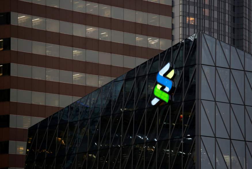 FILE PHOTO: A logo of Standard Chartered is displayed at the financial Central district in Hong Kong, China November 23, 2017. REUTERS/Bobby Yip/File Photo GLOBAL BUSINESS WEEK AHEAD