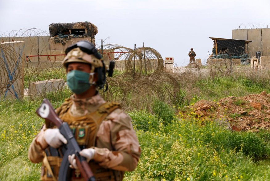 An Iraqi soldier wears a protective face mask and gloves, following the outbreak of coronavirus disease (COVID-19), as he stands guard during the hand over of Qayyarah Airfield West from US-led coalition forces to Iraqi Security Forces