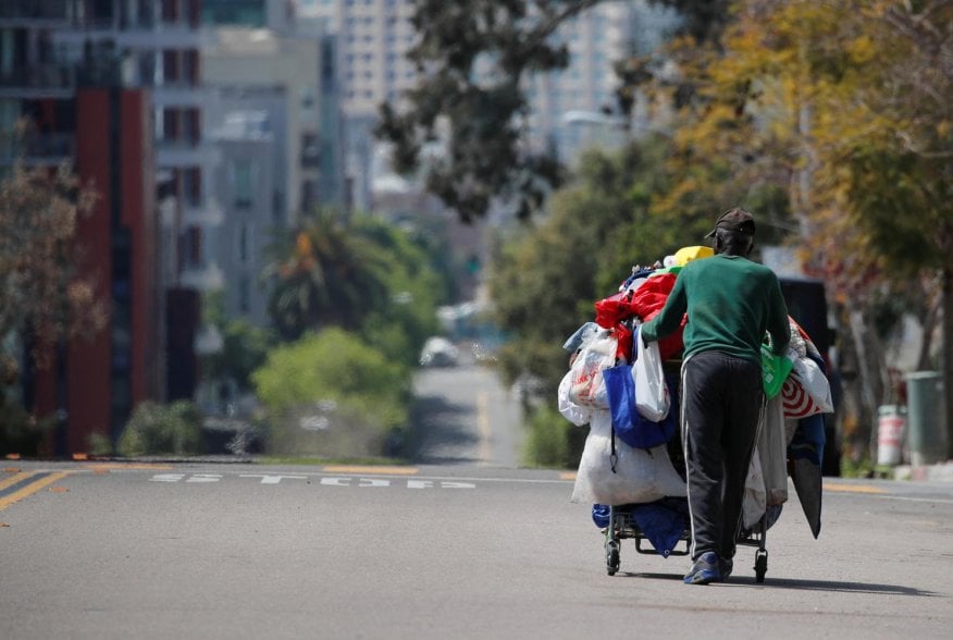 A homeless man pushes a cart full of his belongings along an empty street during the outbreak of the coronavirus disease (COVID-19) in San Diego, California, U.S., April 1, 2020. REUTERS/Mike Blake