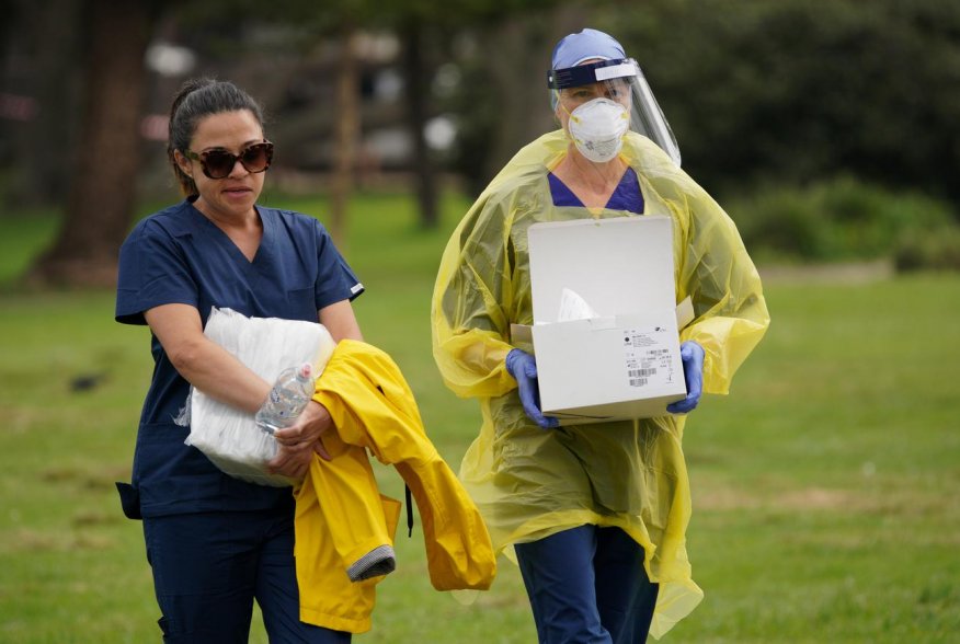 Medical personnel carry equipment to the Bondi Beach drive-through testing centre, where people are queuing up in their vehicles to test for the coronavirus disease (COVID-19), in Sydney, Australia, April 7, 2020. REUTERS/Loren Elliott