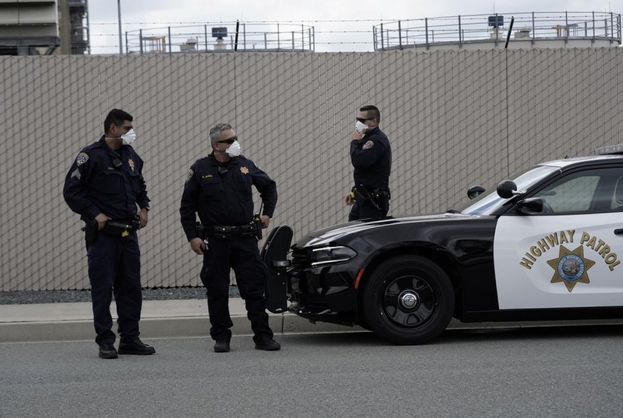 California Highway Patrol officers wearing protective masks wait at a car rally protesting the alleged pepper-spraying of immigrant women detained at the Otay Mesa Detention Center, a ICE (Immigrations & Customs Enforcement) federal detention center priva