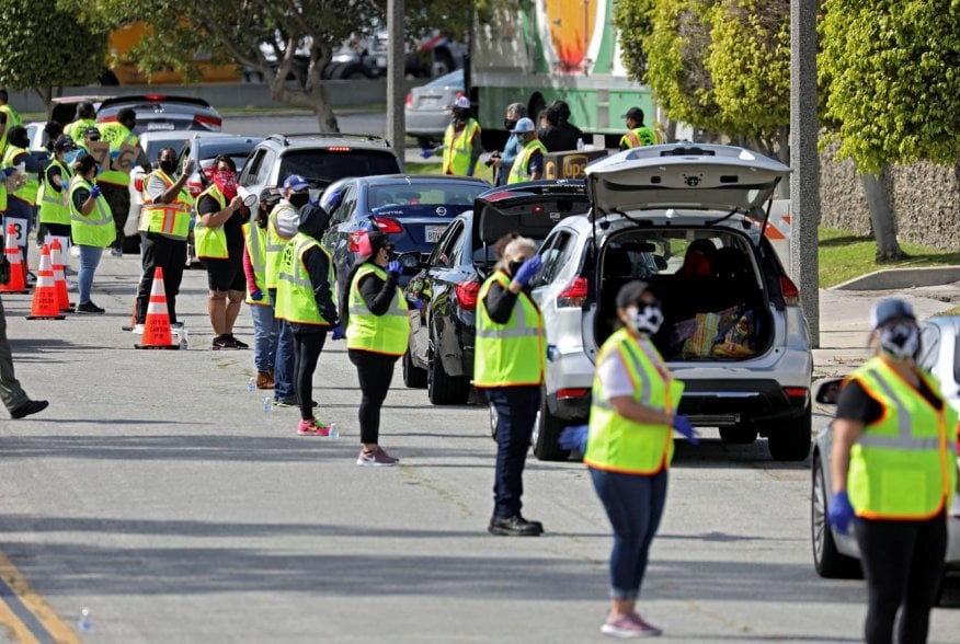 Volunteers control traffic flow as households receive boxes of food at a drive-thru food distribution site from the Los Angeles Regional Food Bank and Los Angeles County Federation of Labor as authorities encourage social distancing to prevent the spread 