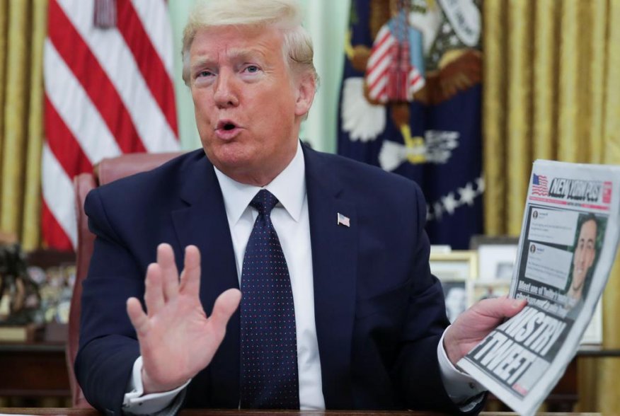 U.S. President Donald Trump holds up a copy of the New York Post newspaper while speaking to reporters while discussing an executive order on social media companies in the Oval Office of the White House in Washington, U.S., May 28, 2020. REUTERS/Jonathan 