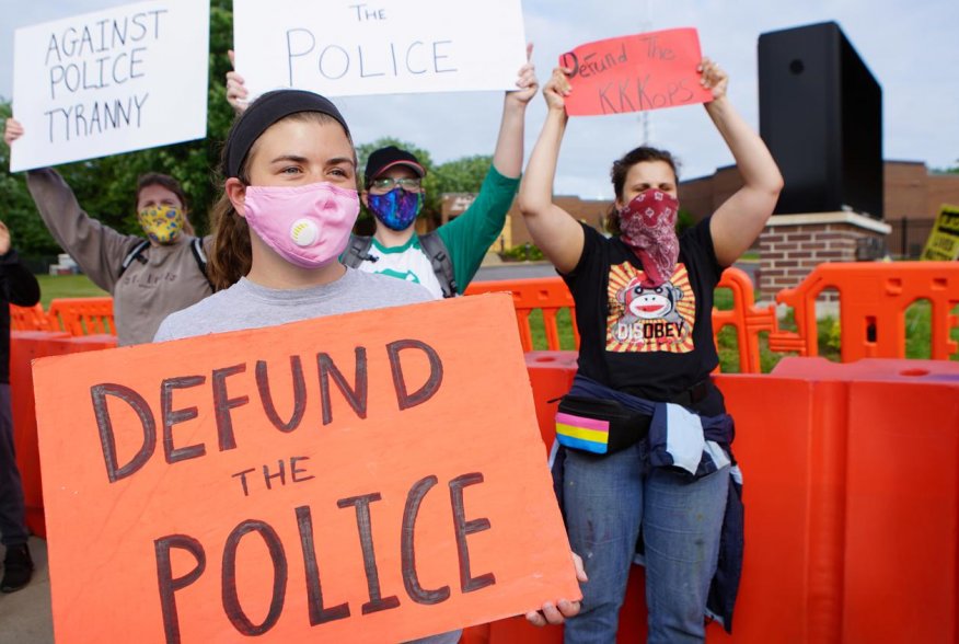 A protester holds a sign calling for the defunding of the police during a protest against the police brutality of a man hit by a Florissant detective and the death in Minneapolis police custody of George Floyd, in Florissant, Missouri, U.S. June 10, 2020.