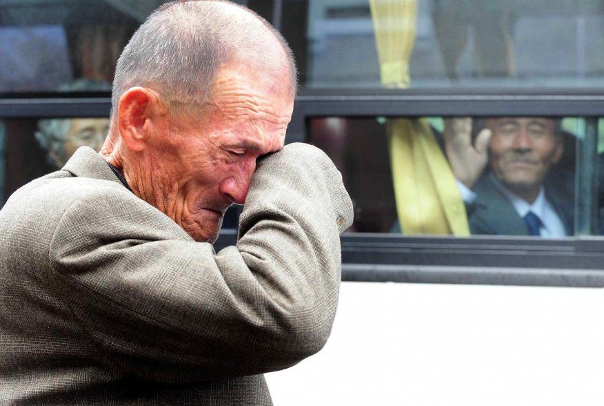 A North Korean man (R) on a bus waves his hand as a South Korean man weeps after a luncheon meeting during inter-Korean temporary family reunions at Mount Kumgang resort October 31, 2010. Kim Ho-Young/Korea Pool via REUTERS