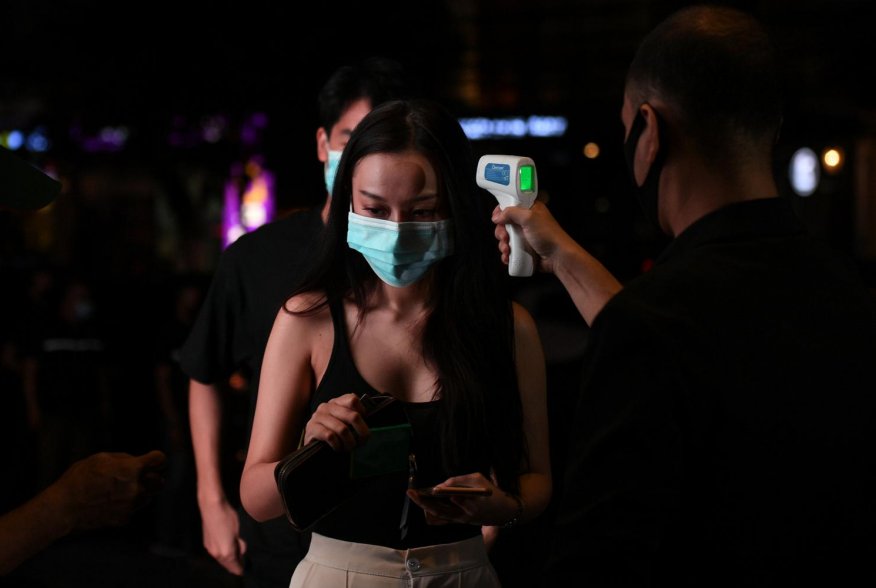 A woman has her temperature checked before entering a bar after the Thai government eased isolation measures and introduced social distancing to prevent the spread of the coronavirus disease (COVID-19), as bars and nightclubs are reopened nationwide, in B