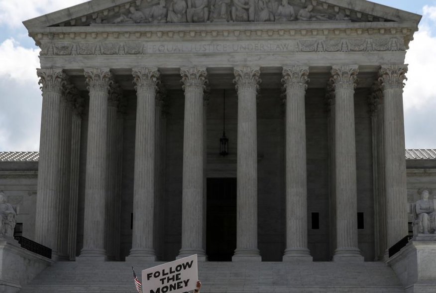 A demonstrator holds a sign reading "follow the money" in anticipation of a U.S. Supreme Court ruling on U.S. President Donald Trump's bid to block his financial records from being obtained by third parties, outside the court in Washington, U.S., July 9, 