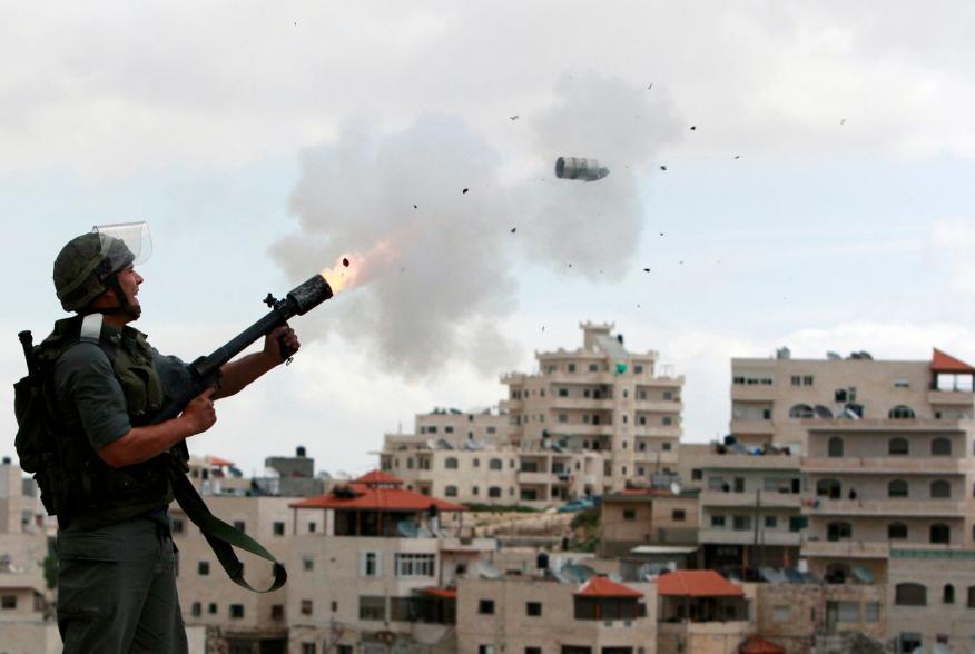 An Israeli border police officer fires tear gas towards Palestinian stone-throwers in East Jerusalem neighbourhood of Issawiya March 16, 2010. Dozens of Palestinian stone-throwers clashed with Israeli police in East Jerusalem on Tuesday on a "day of rage"