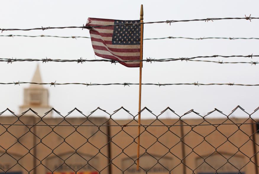 An American flag is seen behind barbed wire at the former U.S. Sather Air Base near Baghdad, Iraq December 14, 2011.