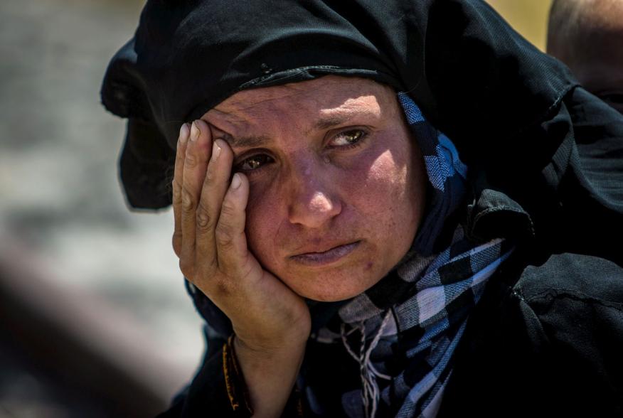 A woman reacts as she rests from walking back to Tel Abyad town, Raqqa governorate, after fleeing Maskana town in the Aleppo countryside June 16, 2015. With a string of victories over Islamic State, Syria's Kurds are proving themselves an ever more depend