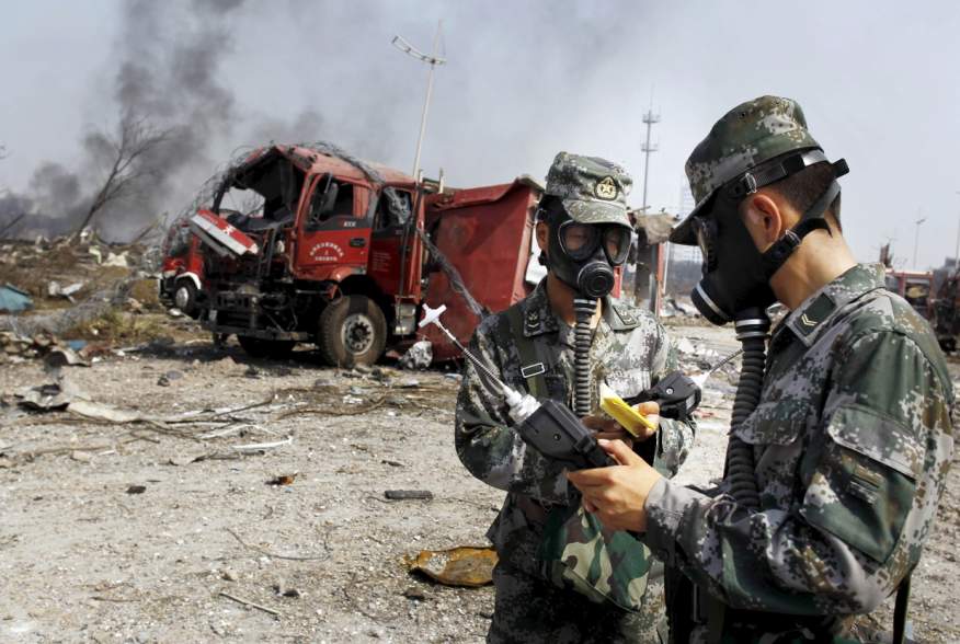 Soldiers of the People's Liberation Army anti-chemical warfare corps work next to a damaged firefighting vehicle at the site of Wednesday night's explosions at Binhai new district in Tianjin, China, August 16, 2015.