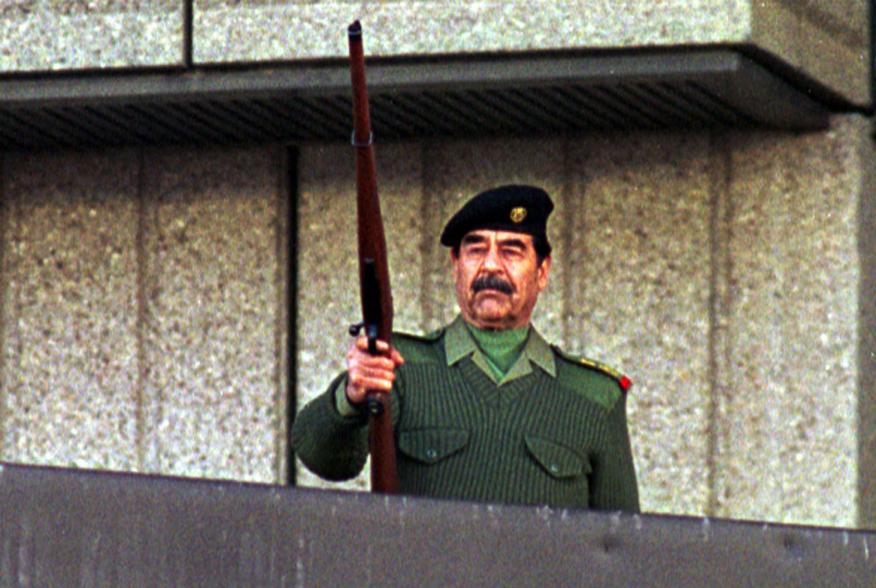 President Saddam Hussein fires a rifle in the air as he salutes Iraqi volunteers who have offered to fight with Paleastinians against Israel troops during a military parade in Baghdad on November 20, 2000. Almost two million men, women and teenagers, some
