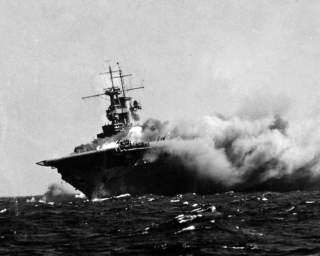  A port bow view of the ship shows her aflame and listing to starboard, 15 September 1942. Men on the flight deck desperately battle the spreading inferno. 