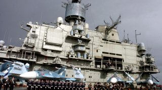 Naval personnel stand in front of the Russian aircraft carrier Kuznetsov in the Syrian city of Tartous on the Mediterranean sea January 8, 2012, in this handout photograph released by Syria's national news agency SANA. QUALITY FROM SOURCE. REUTERS/SANA/Ha