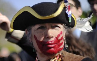 Tea party supporter Susan Clark of California, dressed in colonial garb and face paint, protests against the Obama healthcare legislation as the law's supporters and detractors rally on the sidewalk in front of the Supreme Court, during the third and fina