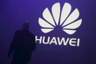 A man walks past a logo during the presentation the Huawei's new smartphone, the Ascend P7, launched by China's Huawei Technologies in Paris, May 7, 2014.