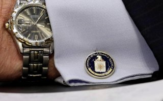 An cufflink with CIA logo is seen on CIA Director John Brennan's shirt as he testifies before the Senate Intelligence Committee hearing on 
