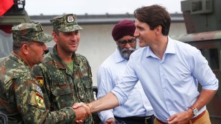 Canada's Prime Minister Justin Trudeau, accompanied by Canada's Defence Minister Harjit Sajjan, shakes hands with Albanian soldiers as he visits NATO eFP Canadian-led battlegroup troops in Adazi military base, Latvia July 10, 2018. REUTERS/Ints Kalnins