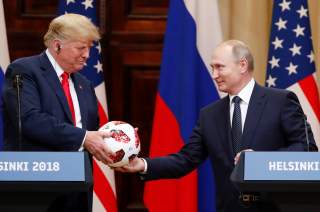U.S. President Donald Trump receives a football from Russian President Vladimir Putin as they hold a joint news conference after their meeting in Helsinki, Finland July 16, 2018. REUTERS/Grigory Dukor