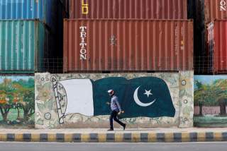 A man walks past a wall of a shipping container's yard painted with a national flag ahead of Pakistan's Independence Day, in Karachi, Pakistan August 6, 2018. REUTERS/Akhtar Soomro