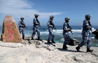 Soldiers of China's People's Liberation Army (PLA) Navy patrol at Woody Island, in the Paracel Archipelago, which is known in China as the Xisha Islands, January 29, 2016. The words on the rock read, 