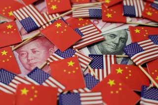 A U.S. dollar banknote featuring American founding father Benjamin Franklin and a China's yuan banknote featuring late Chinese chairman Mao Zedong are seen among U.S. and Chinese flags in this illustration picture taken May 20, 2019. REUTERS/Jason Lee