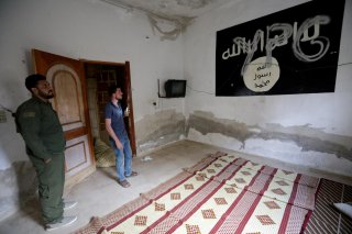 YPG (Kurdish People's Protection Units) is written over a wall painting of ISIS flag inside a house, in the border town of Tal Abyad, Syria, October 16, 2019. REUTERS/Khalil Ashawi