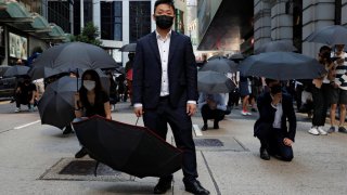 Office workers hold umbrellas as they attend a flash mob anti-government protest after police fired tear gas at the financial Central district in Hong Kong, China, November 11, 2019. REUTERS/Tyrone Siu