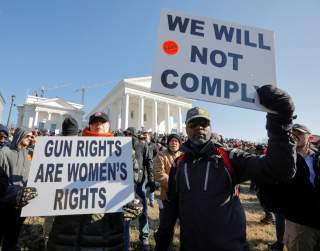 Gun rights advocates hold signs during a rally inside the no-gun zone in front of the Virginia State Capitol building in Richmond, Virginia, U.S. January 20, 2020. REUTERS/Jonathan Drake