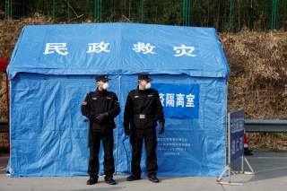 Security personnel stand in front of a disaster relief tent at a checkpoint in Yunxi county, Hunan province, near the border to Hubei province, on virtual lockdown after an outbreak of a new coronavirus, in China, January 28, 2020. REUTERS/Thomas Peter