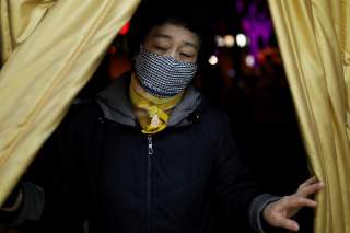 A woman wearing a face mask enters a supermarket, as the country is hit by an outbreak of the new coronavirus, in Beijing, China January 31, 2020. REUTERS/Carlos Garcia Rawlins