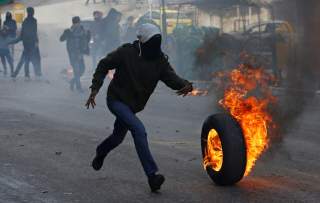 A Palestinian demonstrator rolls a burning tire during a protest against the U.S. President Donald Trump’s Middle East peace plan, in Hebron in the Israeli-occupied West Bank January 31, 2020. REUTERS/Mussa Qawasma