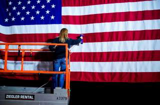 A woman takes the wrinkles from a flag before Pete Buttigieg, Democratic presidential candidate and former South Bend, Indiana mayor attends a watch party on Caucus Day in Des Moines, Iowa, U.S., February 3, 2020. REUTERS/Eric Thayer