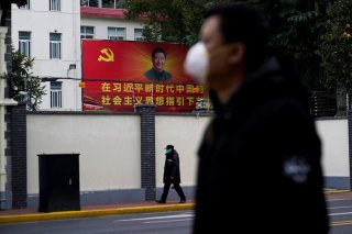 People wearing masks walk past a portrait of Chinese President Xi Jinping on a street as the country is hit by an outbreak of the novel coronavirus in Shanghai, China February 10, 2020. REUTERS/Aly Song