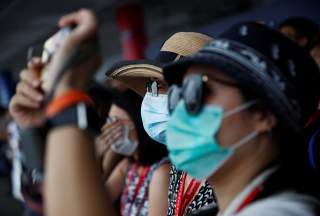 Spectators wearing masks in precaution of the coronavirus outbreak watch an aerial display at the Singapore Airshow in Singapore February 11, 2020. REUTERS/Edgar Su