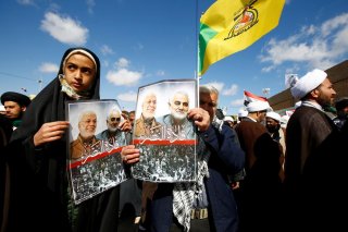 Iranian people carry pictures of the late Iran's Quds Force top commander Qassem Soleimani and Iraqi militia commander Abu Mahdi al-Muhandis, who were killed in a U.S. airstrike at Baghdad airport, during the forty days memorial at the 