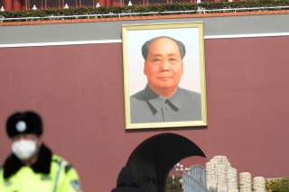 A police officer wearing a face mask stands guard under a giant portrait of the late Chinese chairman Mao Zedong at the Tiananmen Gate as the country is hit by an outbreak of the novel coronavirus, in Beijing, China February 19, 2020. REUTERS/Tingshu Wang