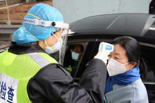 A security officer in a protective mask checks the temperature of a passenger following the outbreak of a new coronavirus, at an expressway toll station on the eve of the Chinese Lunar New Year celebrations, in Xianning, a city bordering Wuhan to the nort