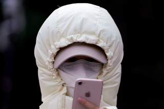 A woman wearing a mask checks her mobile phone in Shanghai, China January 29, 2020. REUTERS/Aly Song