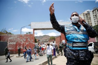 A member of the Bolivarian national police at the gates of a public market asks people to return to their homes during the national quarantine in response to the spread of coronavirus disease (COVID-19) in Caracas, Venezuela, March 21, 2020. REUTERS/Manau