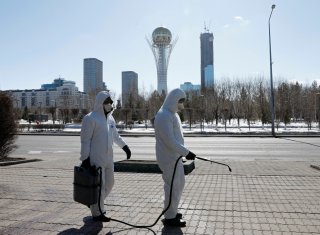 Workers wearing protective suits spray disinfectant on the street to prevent the spread of coronavirus disease (COVID-19), in central Nur-Sultan, Kazakhstan March 24, 2020. REUTERS/Mukhtar Kholdorbekov