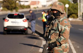 A soldier stands guard as he is joined by police officers to check vehicles as a 21-day lockdown aimed at limiting the spread of coronavirus disease (COVID-19) takes effect in Cape Town, South Africa, March 27,2020.REUTERS/Mike Hutchings