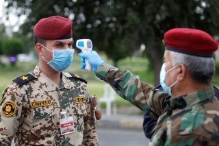 An Iraqi soldier wears a protective face mask and gloves as he checks the temperature of an Iraqi officer, during a curfew imposed to prevent the spread of the coronavirus disease (COVID-19), in Baghdad, Iraq March 27, 2020. REUTERS/Khalid al-Mousily