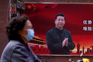 A woman wearing a protective mask is seen past a portrait of Chinese President Xi Jinping on a street as the country is hit by an outbreak of the coronavirus, in Shanghai, China March 12, 2020. REUTERS/Aly Song